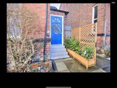 a brick house with a blue door and a gate at The Hollies in Crosby