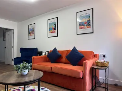 a living room with an orange couch and two tables at The Old Brewery - A St David Aparthotel in Barrow in Furness
