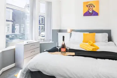 a bedroom with a bed with a bottle of wine on a table at Leisure Stays with Wifi Close to Anfield, sleeps 8 in Liverpool