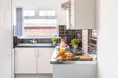 a kitchen with white cabinets and a plate of food on a counter at Leisure Stays with Wifi Close to Anfield, sleeps 8 in Liverpool