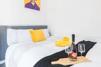 a white bed with two glasses and a tray with wine bottles at Leisure Stays with Wifi Close to Anfield, sleeps 8 in Liverpool