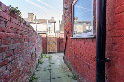 an alley with a red brick wall and a window at Leisure Stays with Wifi Close to Anfield, sleeps 8 in Liverpool