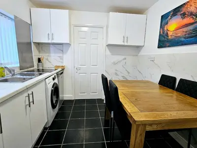 a kitchen with a sink and a wooden table at Comfort in Liverpool