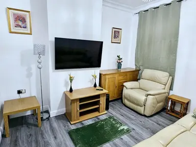 a living room with a tv and a couch and a chair at Comfort in Liverpool