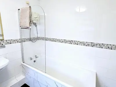 a white bathroom with a tub and a sink at Comfort in Liverpool