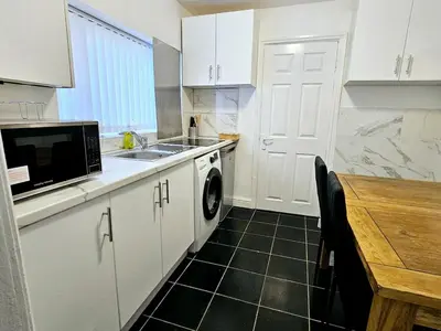 a kitchen with a sink and a washing machine at Comfort in Liverpool