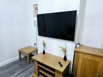 a living room with a flat screen tv and two vases with flowers at Comfort in Liverpool