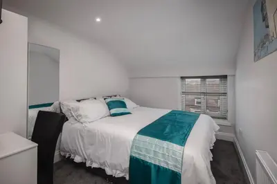 a white bedroom with a bed and a window at Polaris Apartments in Blackpool