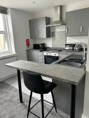 a kitchen with a table and a black chair at Polaris Apartments in Blackpool