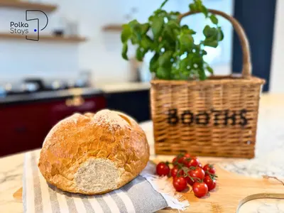a loaf of bread sitting on a table next to a basket of tomatoes at No 2 PolkaStays Ivy Farm Rosewood Cottage in Plumpton