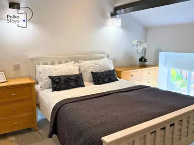 a bedroom with a large bed with black and white pillows at No 2 PolkaStays Ivy Farm Rosewood Cottage in Plumpton