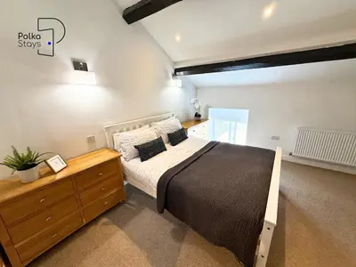a bedroom with a large bed and a wooden dresser at No 2 PolkaStays Ivy Farm Rosewood Cottage in Plumpton