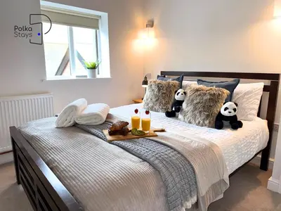 a bed with two stuffed panda bears sitting on it at No 3 PolkaStays Ivy Farm Coach House Family Suite in Plumpton