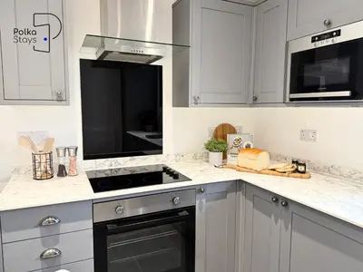 a kitchen with white cabinets and a stove top oven at No 3 PolkaStays Ivy Farm Coach House Family Suite in Plumpton