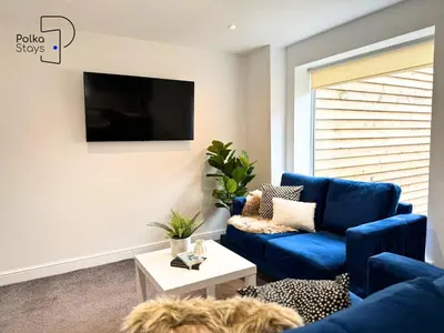 a living room with a blue couch and a tv at No 3 PolkaStays Ivy Farm Coach House Family Suite in Plumpton