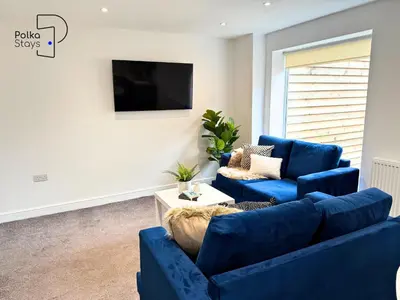 a living room with two blue couches and a tv at No 3 PolkaStays Ivy Farm Coach House Family Suite in Plumpton