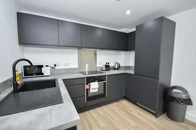 a kitchen with black cabinets and a sink at Modern & Spacious 2 Bedroom Liverpool Apartment in Liverpool