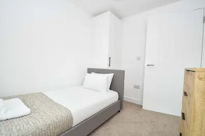 a white bedroom with a bed and a cabinet at Modern & Spacious 2 Bedroom Liverpool Apartment in Liverpool