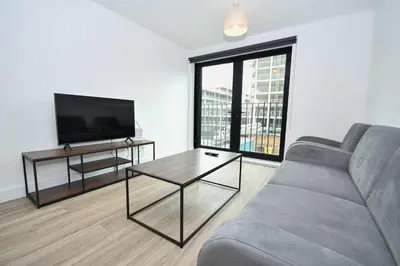 a living room with a couch and a flat screen tv at Modern & Spacious 2 Bedroom Liverpool Apartment in Liverpool