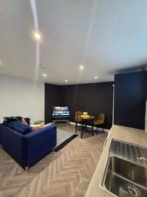 a living room with a blue couch and a tv at Courtyard High Spec Apartment in Town Centre in Blackburn