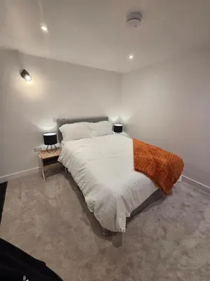 a bedroom with a large white bed with two lamps at Courtyard High Spec Apartment in Town Centre in Blackburn
