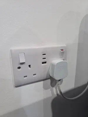 a white outlet on a wall with a wire at Courtyard High Spec Apartment in Town Centre in Blackburn