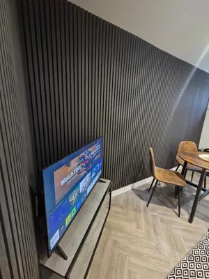 a television in a room with a table and a chair at Courtyard High Spec Apartment in Town Centre in Blackburn