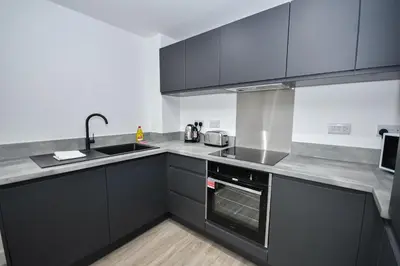 a kitchen with black cabinets and a sink at Bright & Spacious 2 Bed Apartment in Liverpool in Liverpool