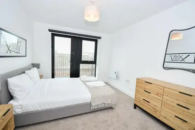 a bedroom with a bed and a dresser and a mirror at Bright & Spacious 2 Bed Apartment in Liverpool in Liverpool