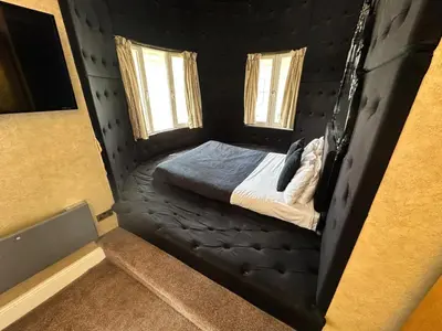 a black bed in a room with two windows at White Star Line Hotel in Liverpool