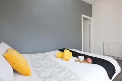 a white bed with yellow pillows and towels on it at Contractors House with Parking City Area, sleeps 8 in Liverpool