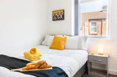 a bedroom with two beds with towels and a window at Contractors House with Parking City Area, sleeps 8 in Liverpool