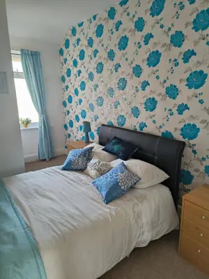 a bedroom with a bed with blue floral wallpaper at Springfield house holiday apartments in Blackpool