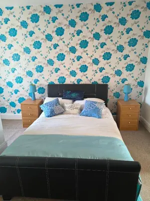 a bedroom with a bed with blue flowers on the wall at Springfield house holiday apartments in Blackpool
