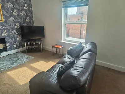 a leather couch in a living room with a window at Springfield house holiday apartments in Blackpool