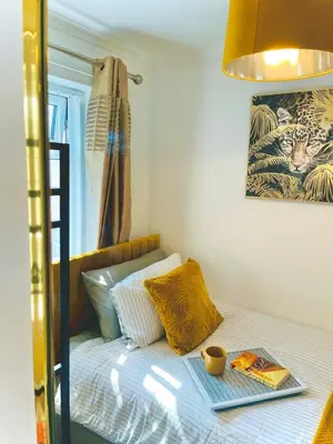 a bed with a book and a cup on it at Ideal 4 Bed Home sleeps 7 Nr Middlebrook Stadium in Lostock