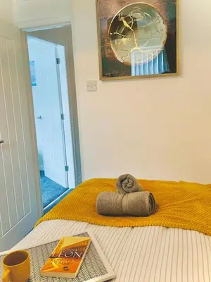 a bed with a towel and a book on it at Ideal 4 Bed Home sleeps 7 Nr Middlebrook Stadium in Lostock