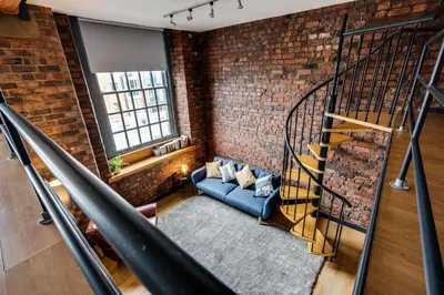a brick room with a staircase and a blue couch at Liverpool Warehouse Flat - Sleeps 5, WiFi, Free On-Site Parking in Liverpool