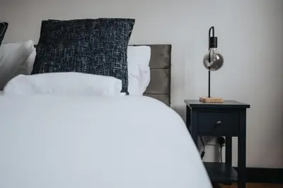 a bed with a black pillow and a side table at Liverpool Warehouse Flat - Sleeps 5, WiFi, Free On-Site Parking in Liverpool
