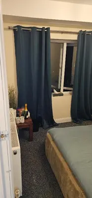 a bedroom with a bed and a window with blue curtains at Sure stay property in Bolton