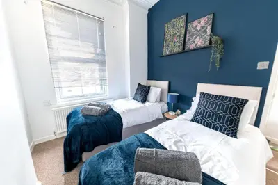 two beds in a room with blue walls at Cozy & Modern Accommodation in Barrow-in-Furness in Barrow in Furness
