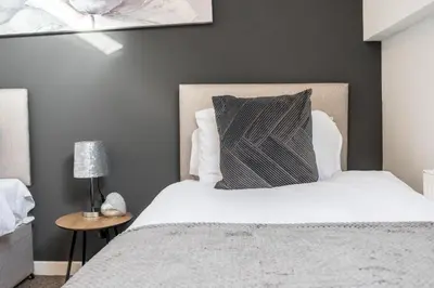 a bedroom with a large bed with a gray wall at Cozy & Modern Accommodation in Barrow-in-Furness in Barrow in Furness