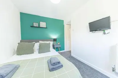 a bedroom with a large bed with a blue wall at Cozy & Modern Accommodation in Barrow-in-Furness in Barrow in Furness
