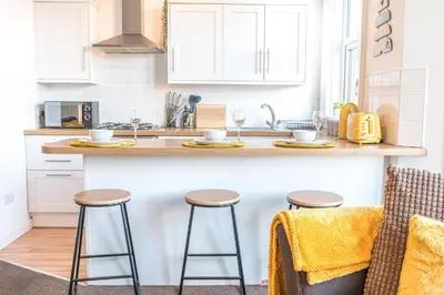 a kitchen with a counter and stools in a kitchen at Cozy & Modern Accommodation in Barrow-in-Furness in Barrow in Furness