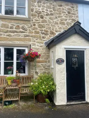 a stone house with a bench and a black door at Squirrel Cottage in Ribchester