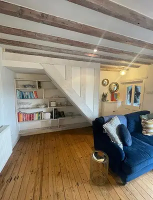 a living room with a blue couch and a wooden floor at Squirrel Cottage in Ribchester