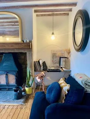 a living room with a blue couch and a fireplace at Squirrel Cottage in Ribchester