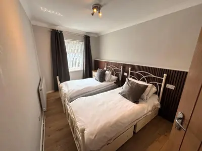 two twin beds in a room with a window at SmithStayz Poulton in Poulton le Fylde
