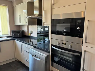 a kitchen with stainless steel appliances and black counter tops at SmithStayz Poulton in Poulton le Fylde