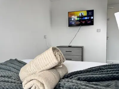 a bed with a blanket and a tv on the wall at 6B 3Bath - Free Parking - TVs In EVERY Room in Liverpool